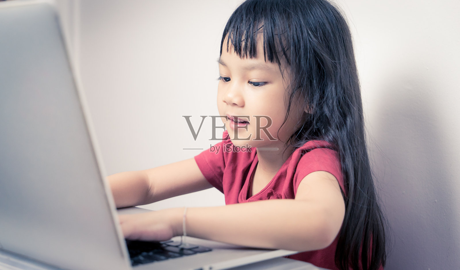 快乐的亚洲女孩正在用笔记本电脑。照片摄影图片