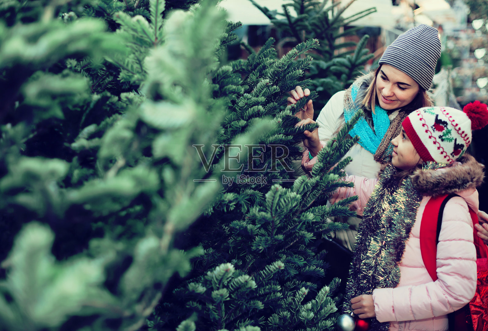 一个女人带着女儿在集市上买圣诞树照片摄影图片