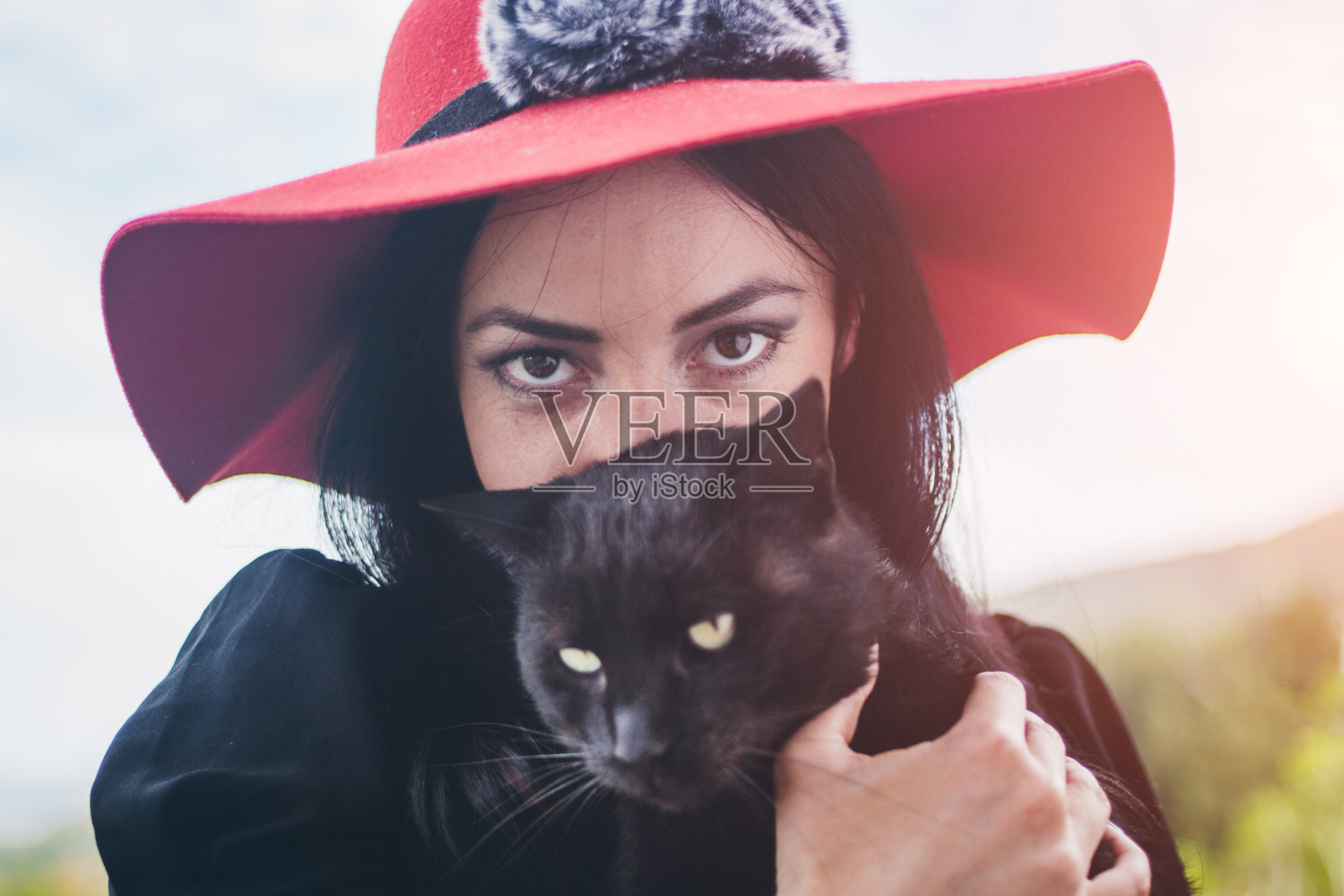 年轻美丽迷人的黑发女人抱着黑猫照片摄影图片