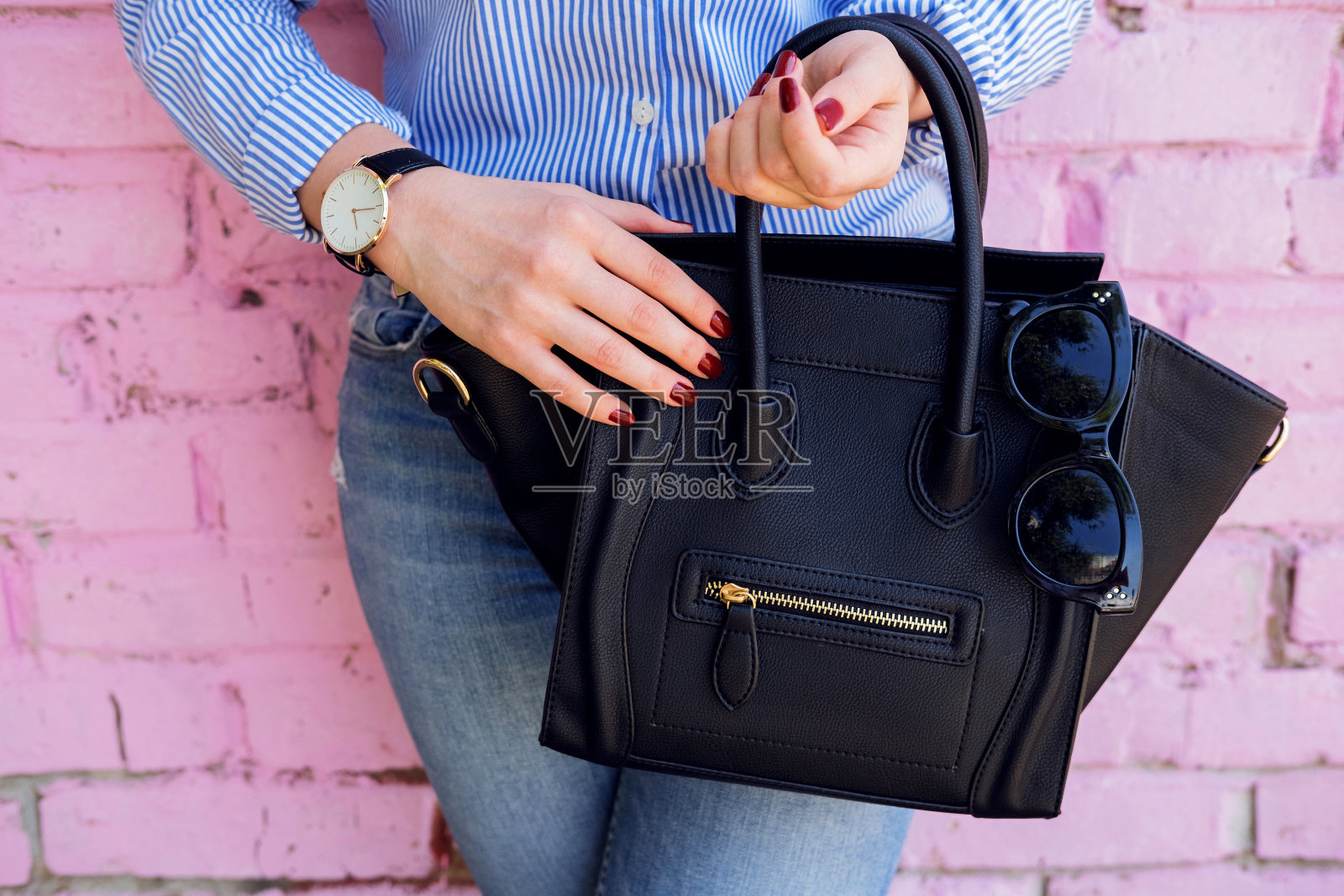 紧靠黑色皮包在时尚女性的手中。照片摄影图片