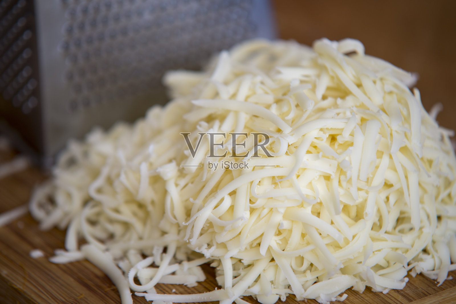 切碎的马苏里拉奶酪用磨碎器放在切菜板上照片摄影图片
