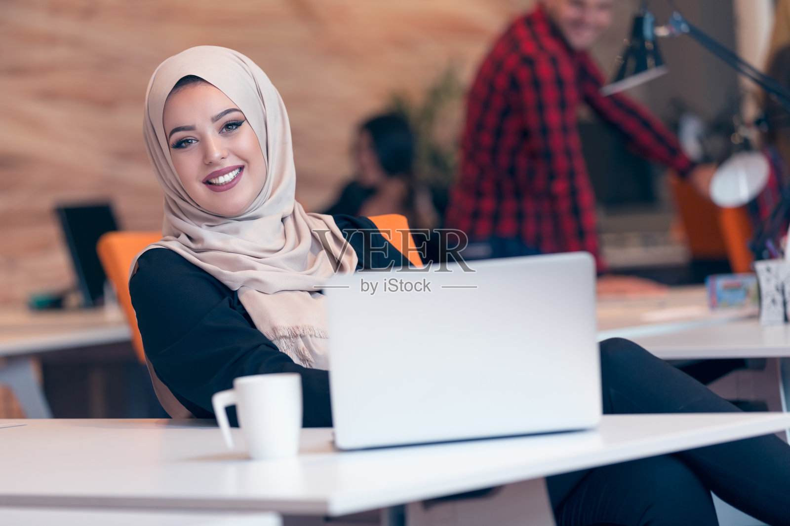 年轻的阿拉伯女商人戴着头巾，在创业办公室工作。照片摄影图片