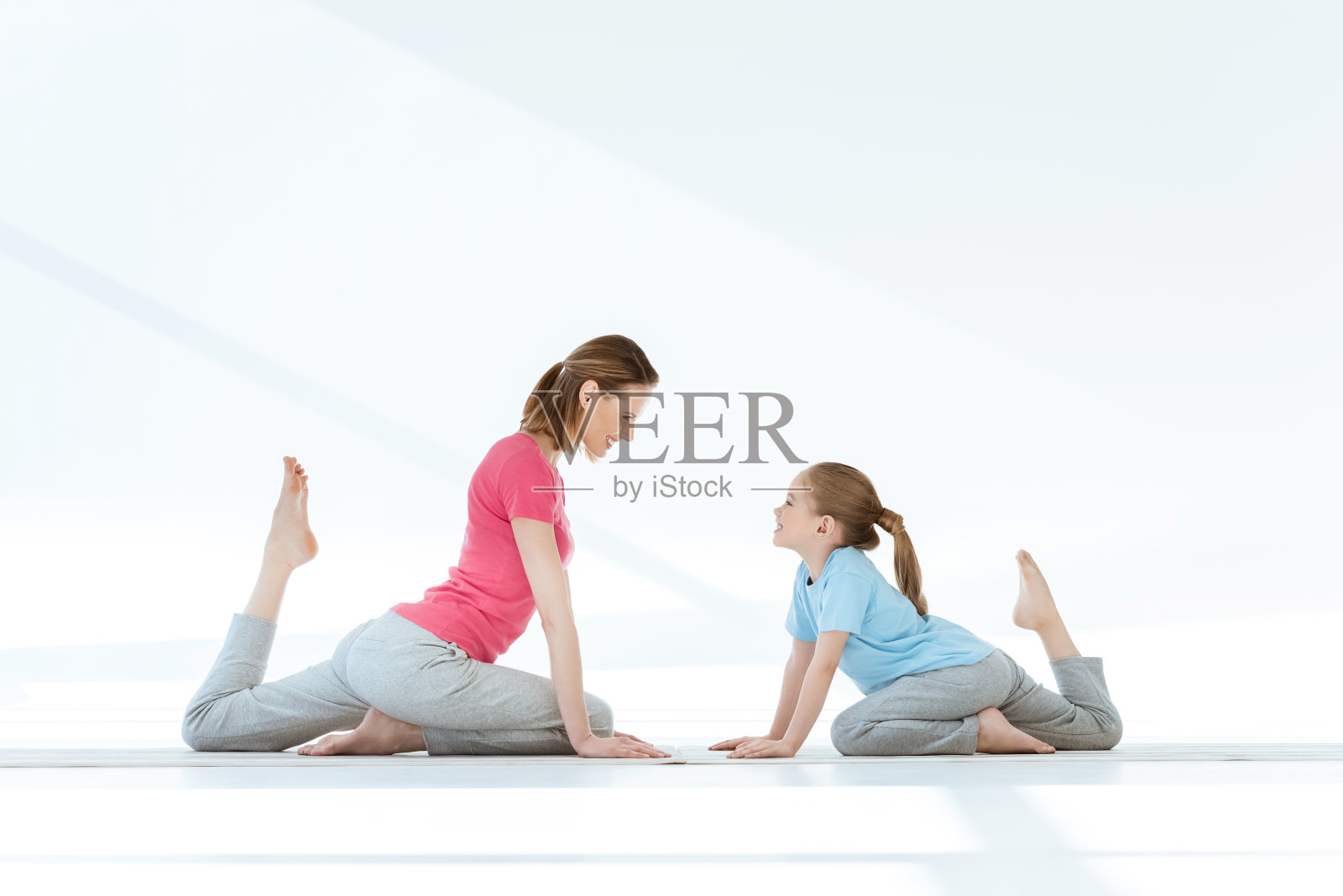 微笑的母亲和女儿在垫子上练习鸽子瑜伽姿势照片摄影图片