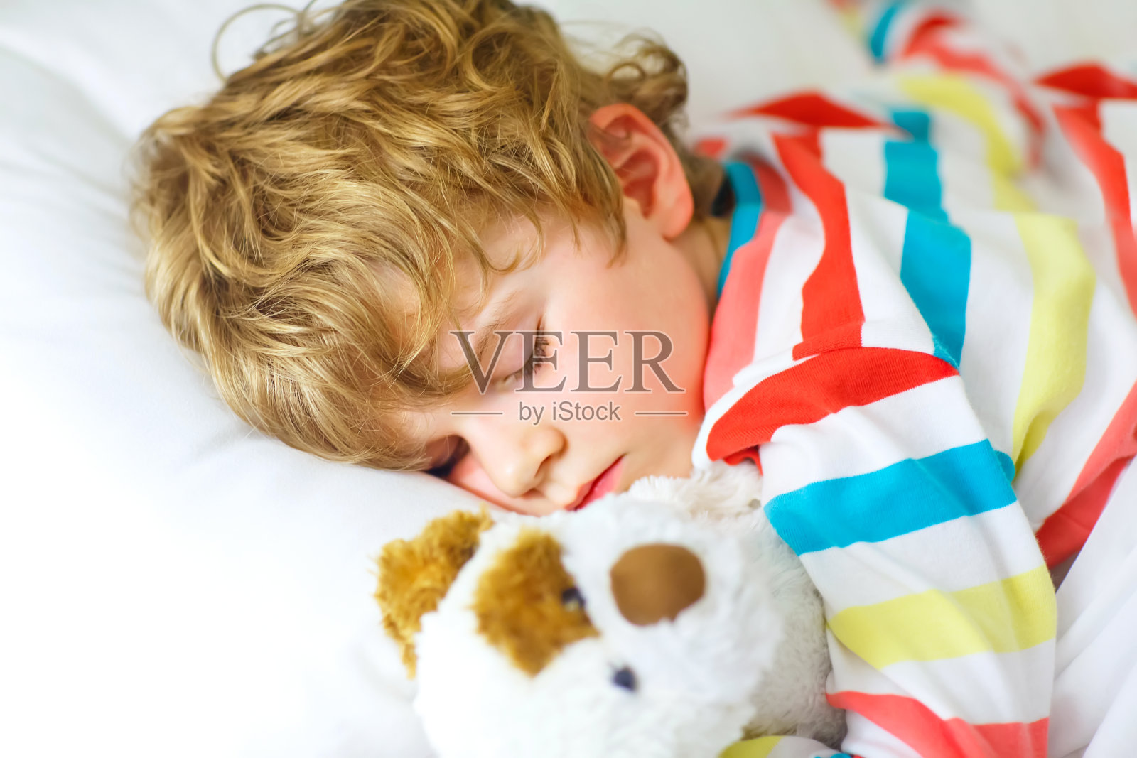 金发小男孩穿着五颜六色的睡衣睡觉照片摄影图片