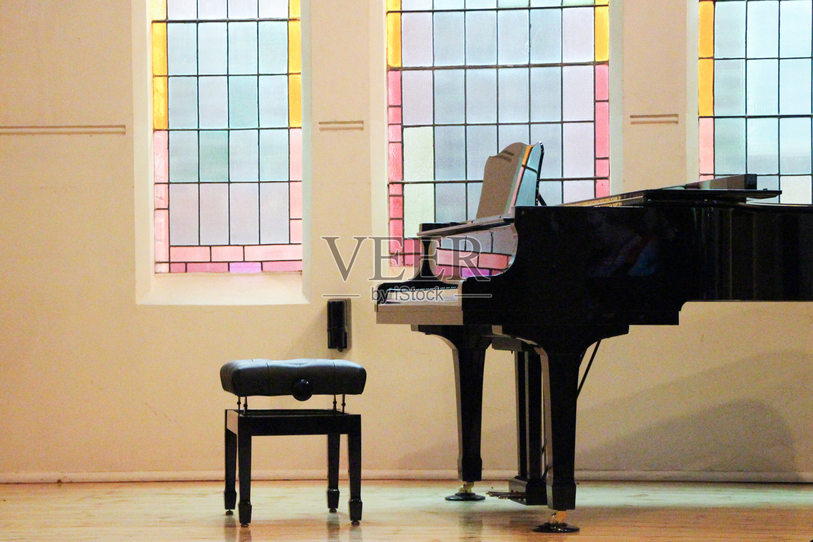 沐浴在彩色玻璃灯光下的教堂钢琴照片摄影图片
