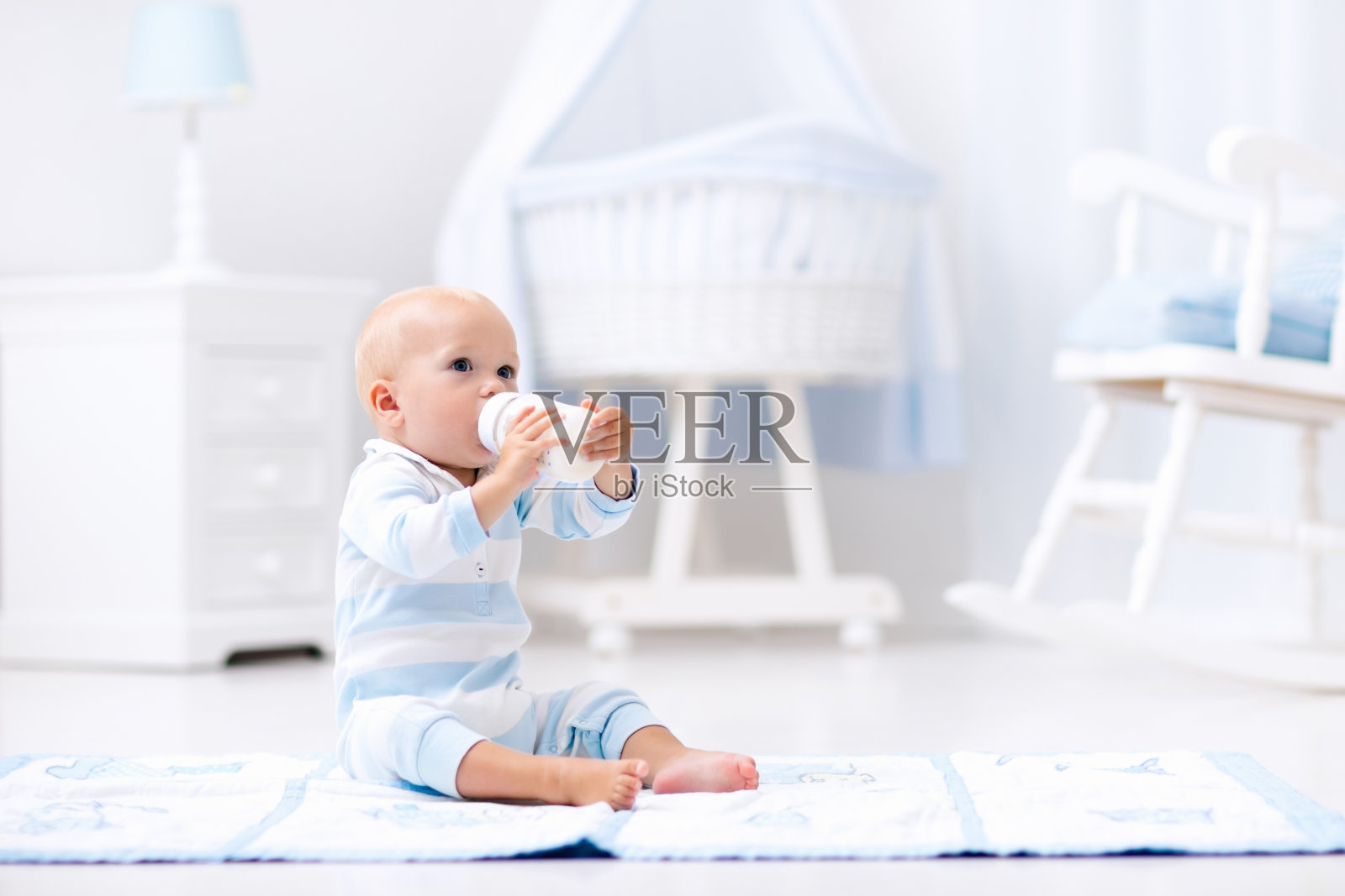 男婴在阳光明媚的托儿所喝牛奶照片摄影图片