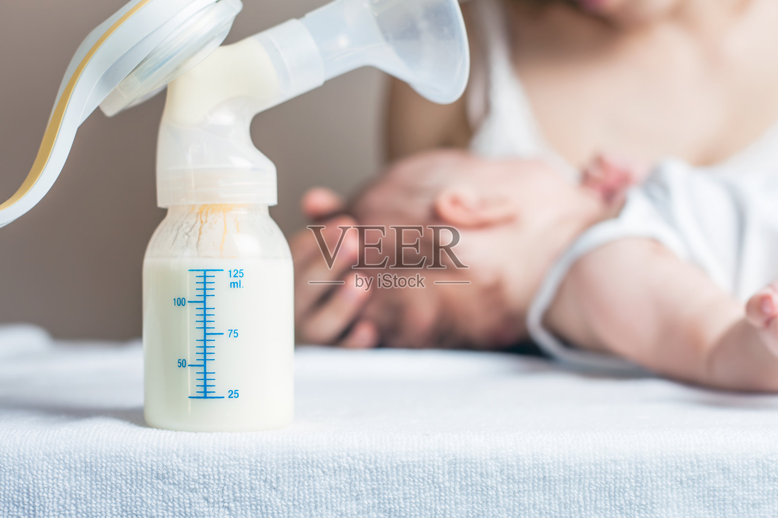 手动吸乳器与母乳，母亲和婴儿在背景照片摄影图片