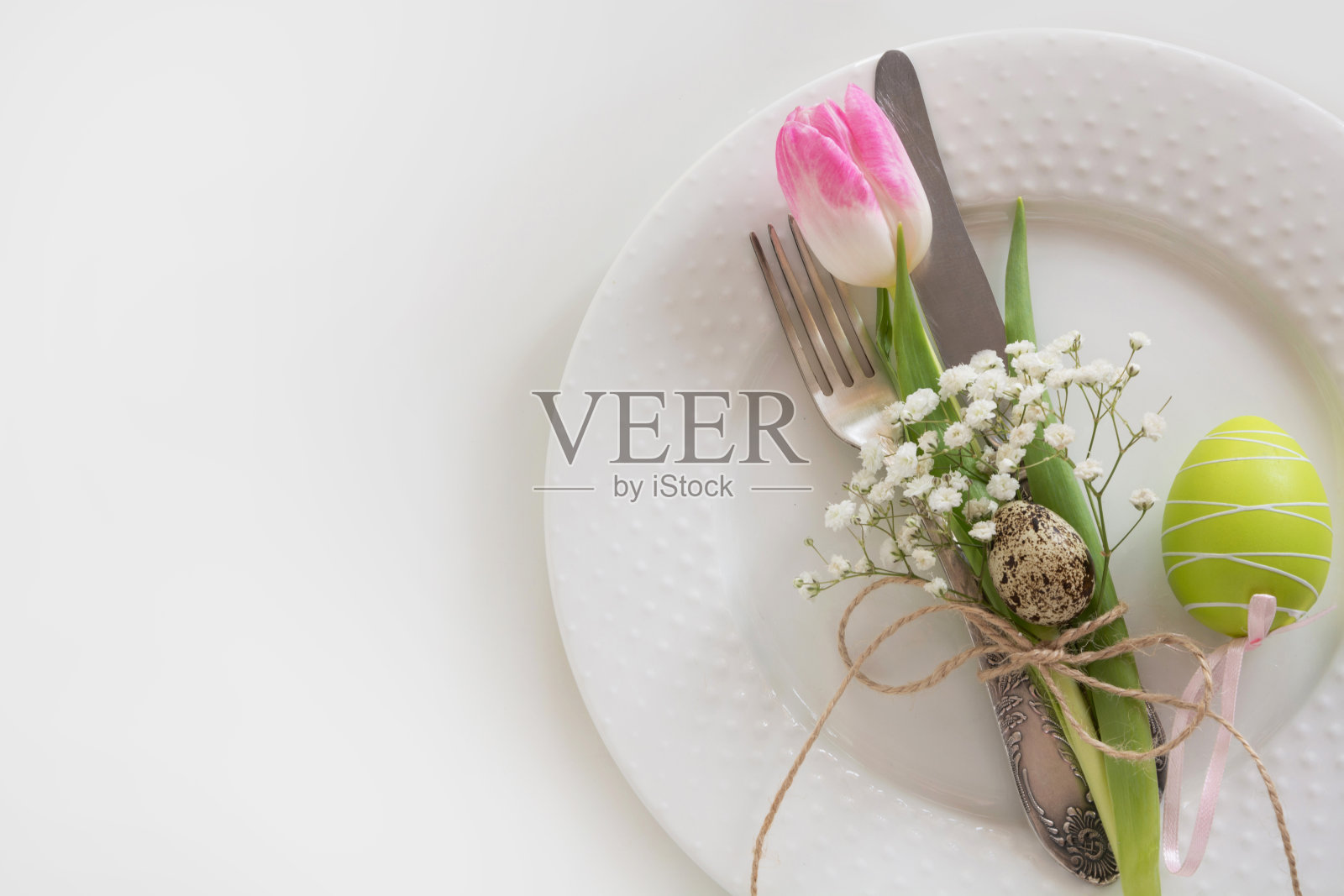 复活节餐桌上的白色背景是粉红色的丝带和郁金香。春天的浪漫晚餐。俯视图和复制空间的文本。照片摄影图片