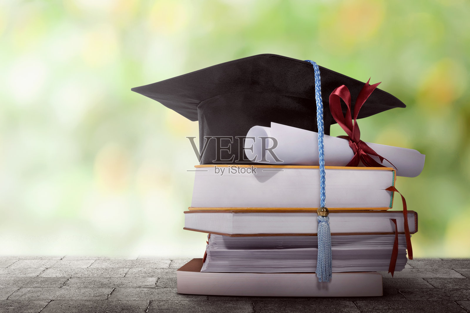 毕业帽与学位论文放在一堆书上照片摄影图片