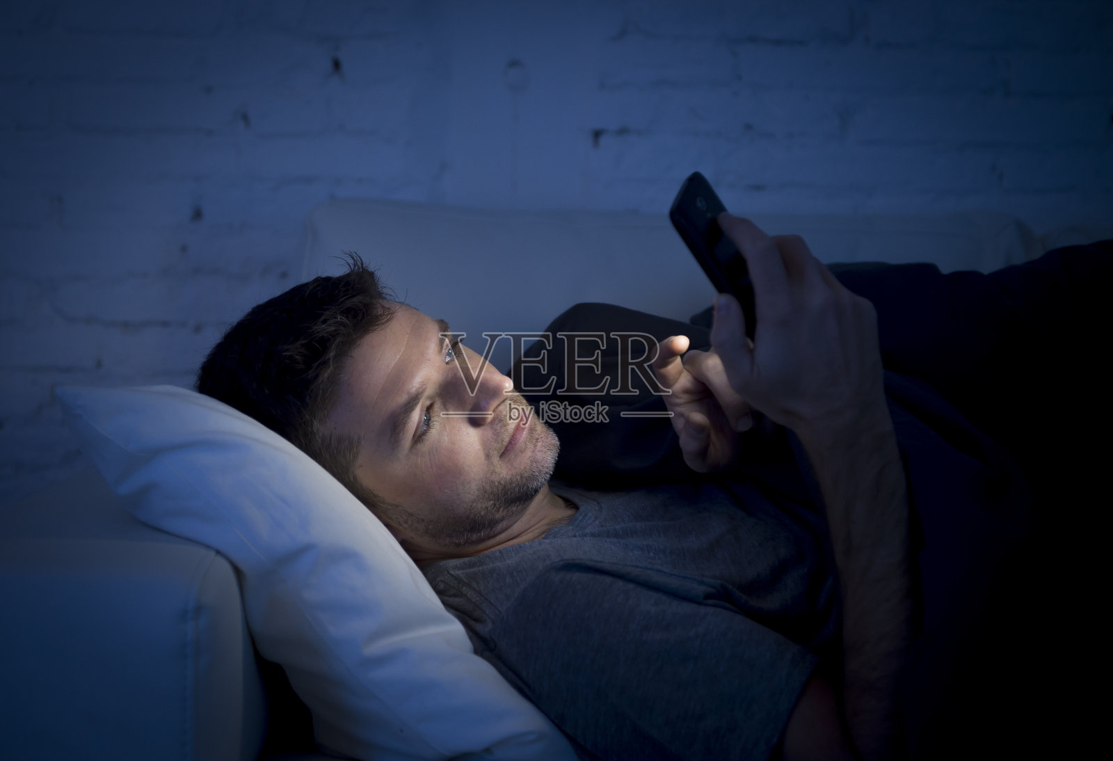 深夜坐在沙发上用手机上网的男人照片摄影图片