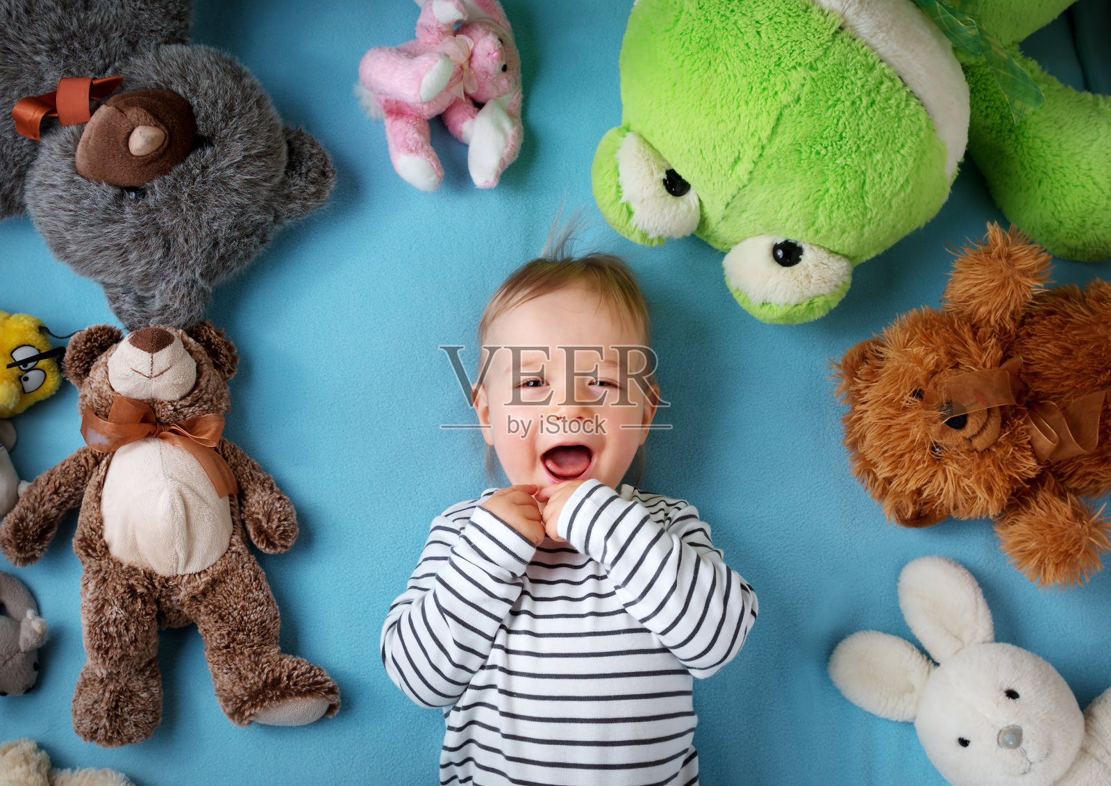 快乐的一岁男孩躺在许多毛绒玩具照片摄影图片