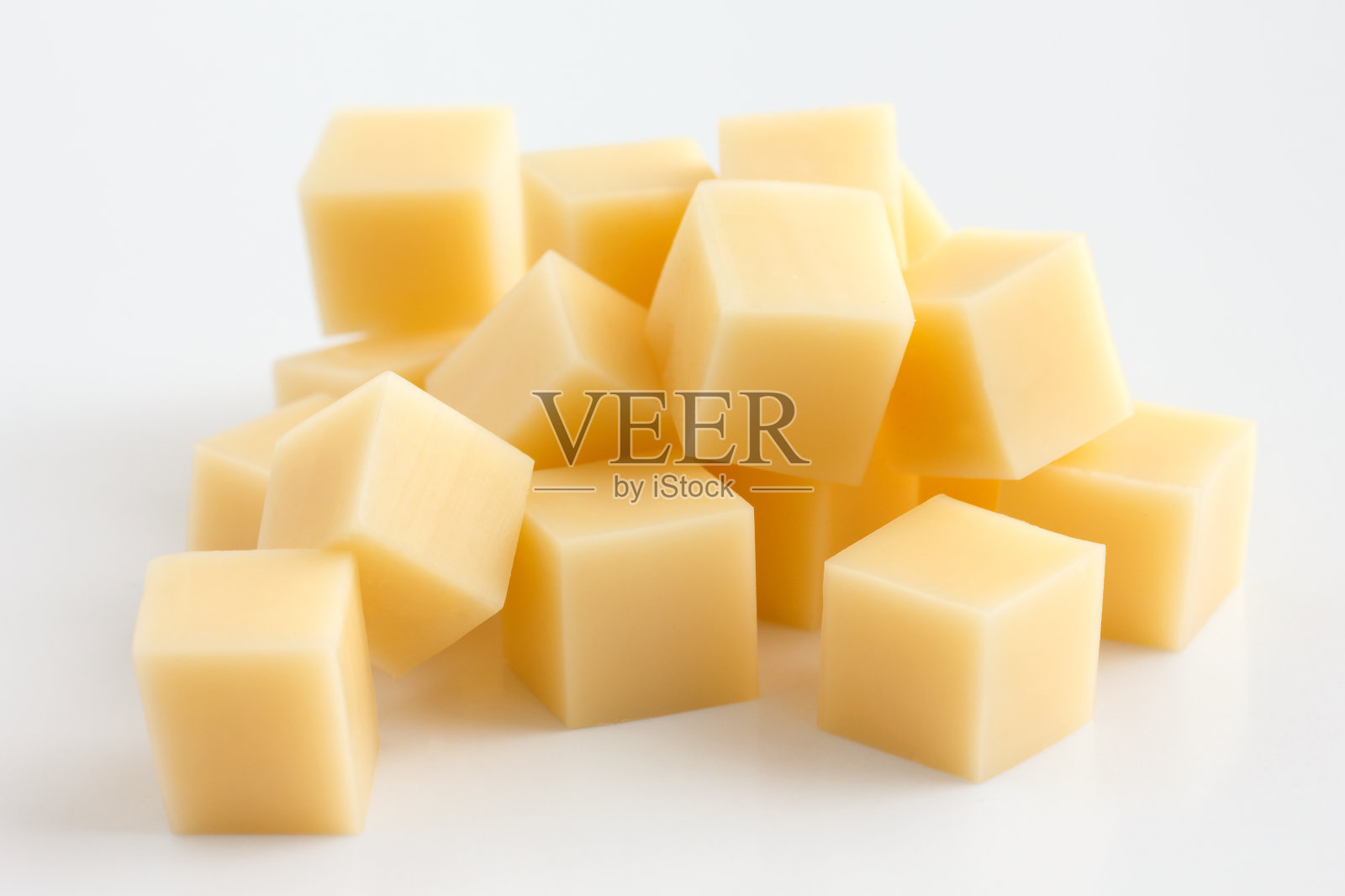 黄色的奶酪块随意堆放在白色的奶酪上。照片摄影图片
