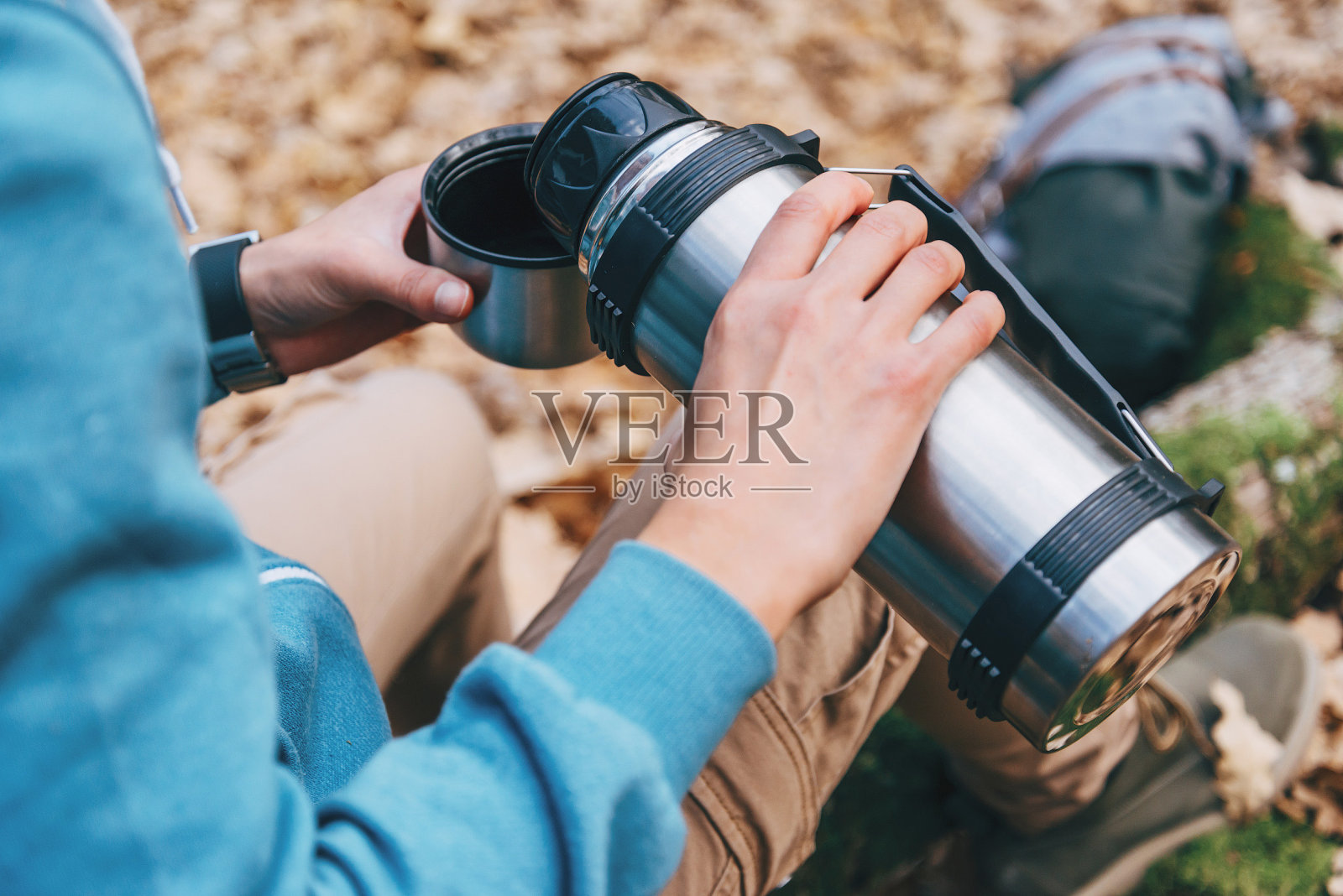 一个徒步妇女在户外把热水瓶里的茶倒进杯子里照片摄影图片