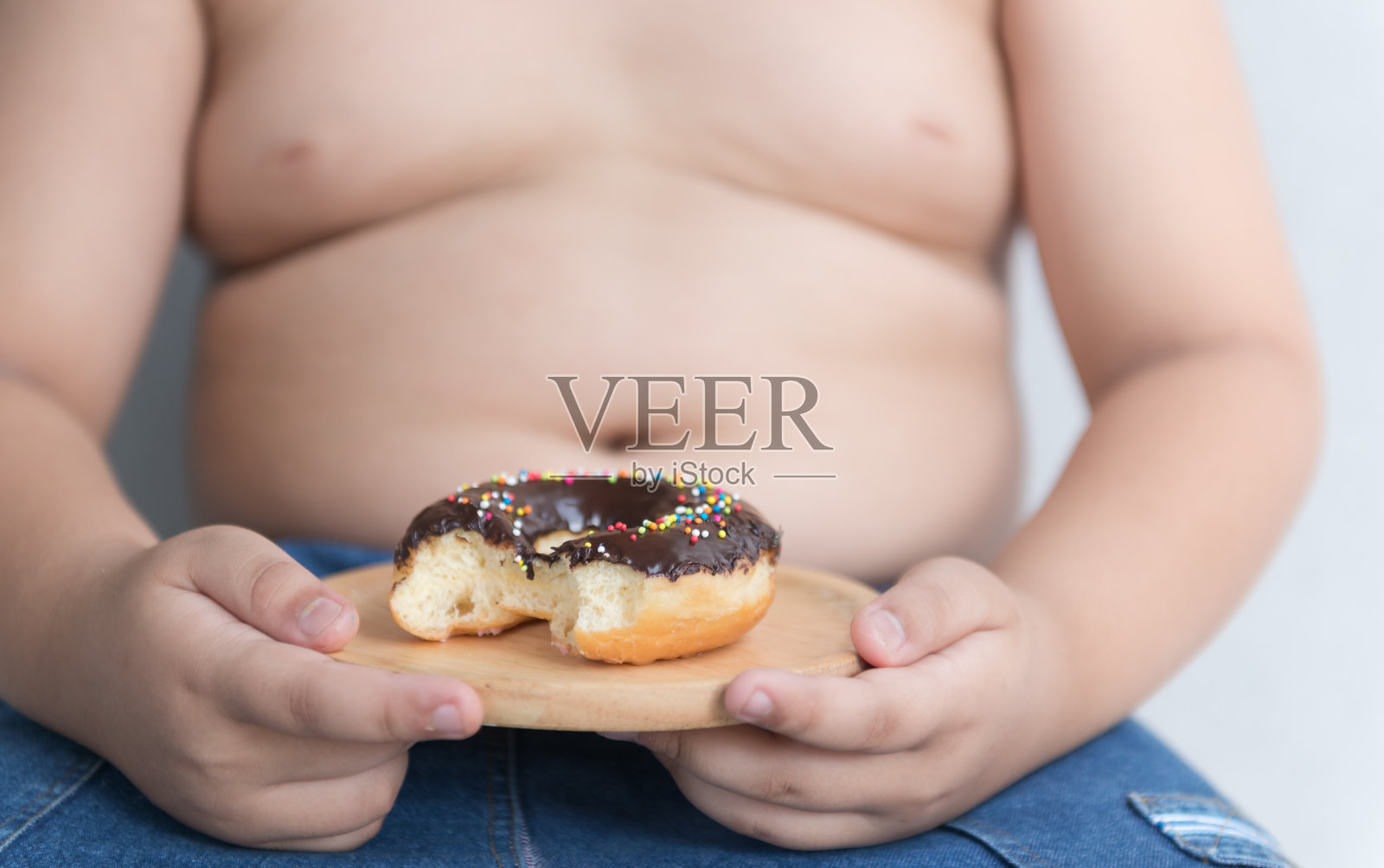 手里拿着甜甜圈的胖子。照片摄影图片