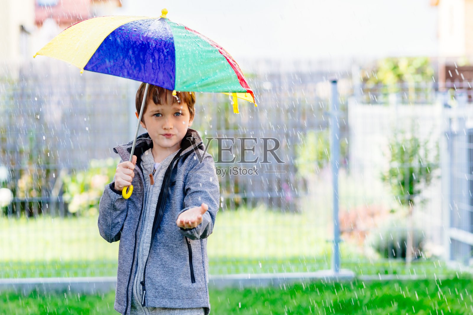 一个七岁的小男孩站在雨中照片摄影图片