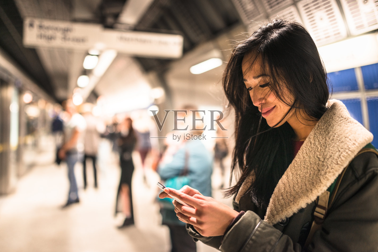 一个女人在地铁站里用智能手机照片摄影图片