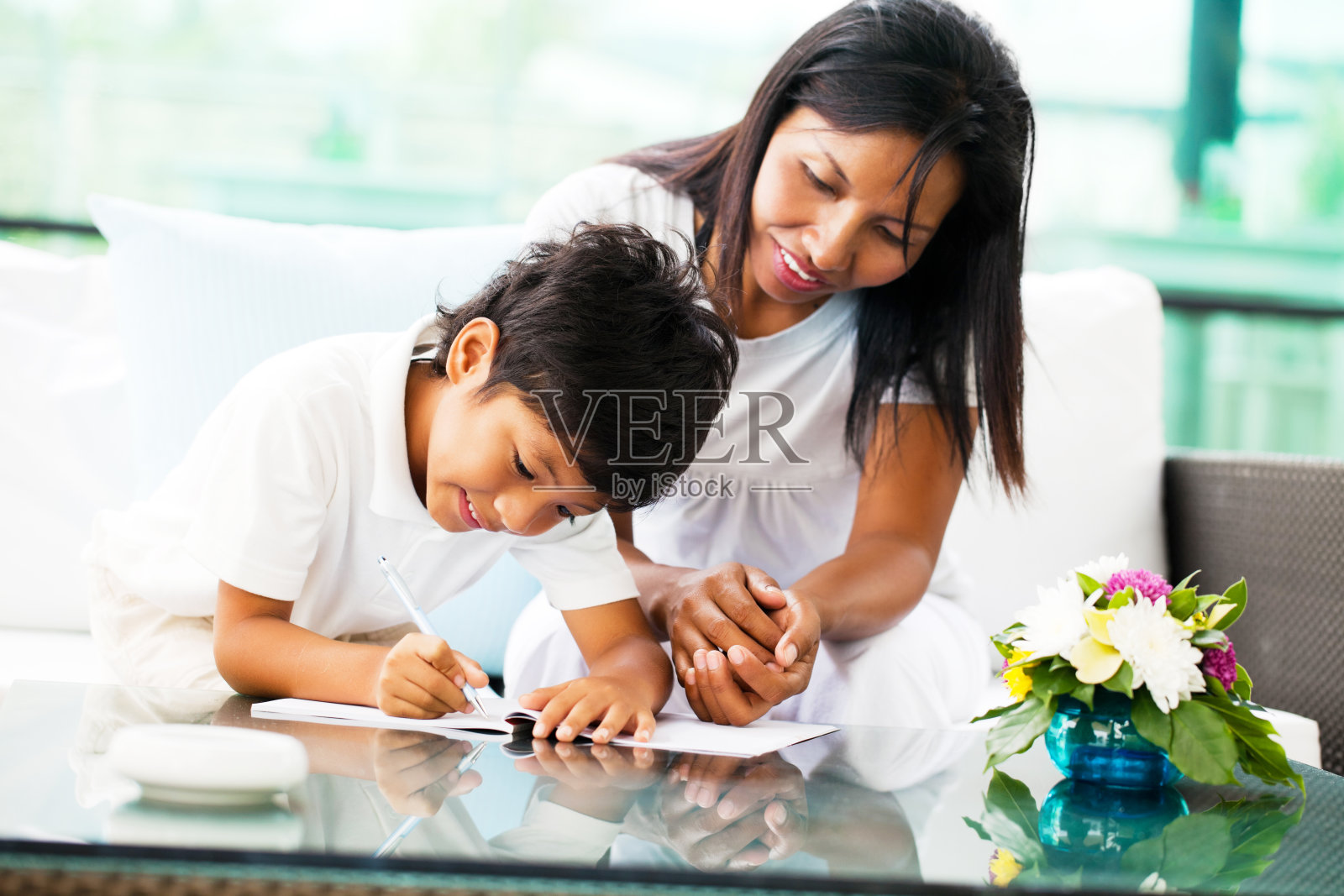 一位亚裔母亲在帮助儿子做家庭作业。照片摄影图片
