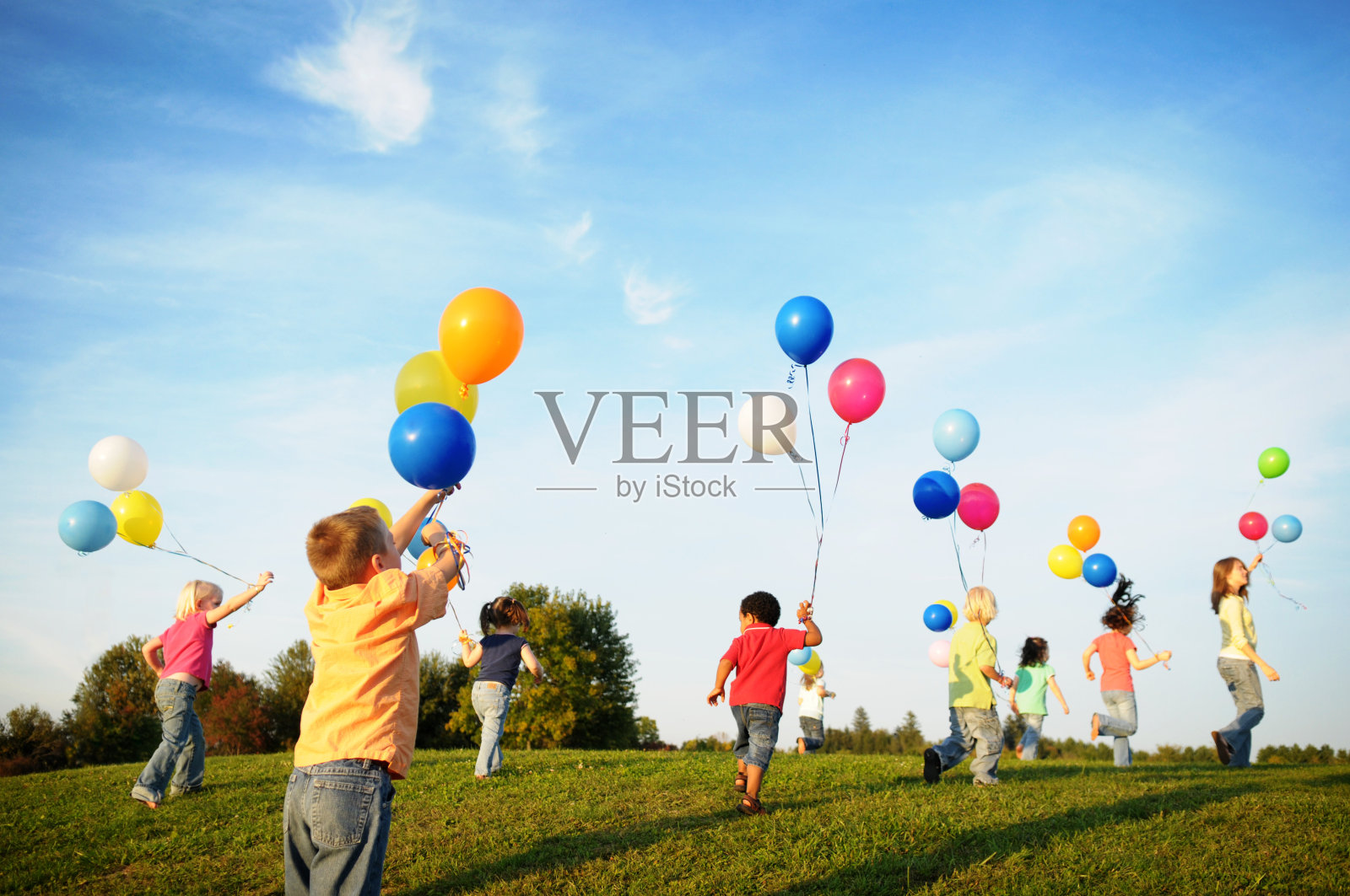 一群孩子拿着气球在阳光下奔跑照片摄影图片