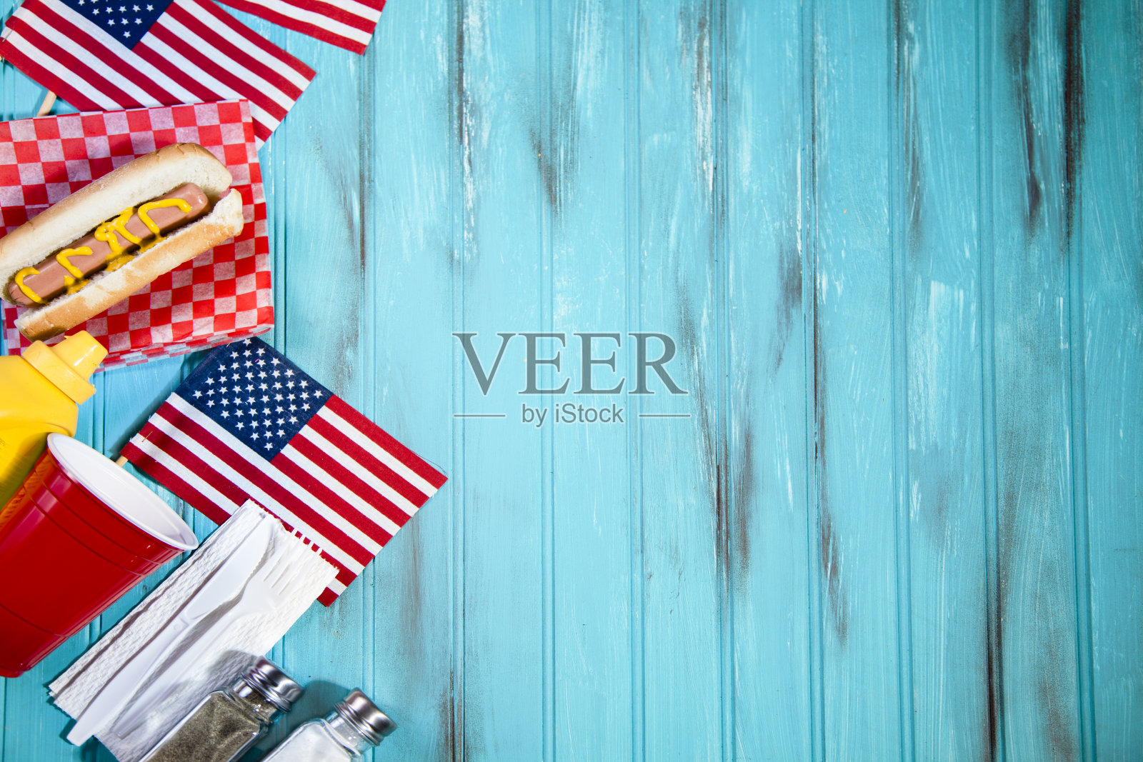 暑假野餐。热狗，美国国旗。蓝色的木桌上。照片摄影图片