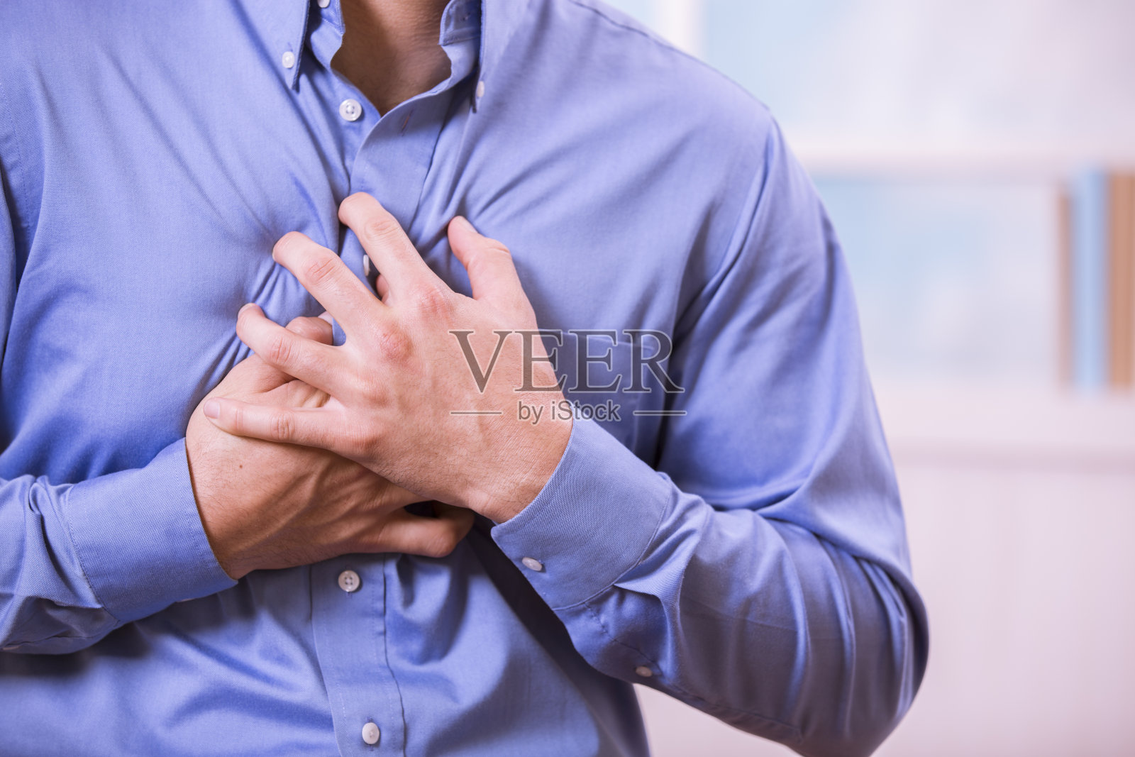 医疗保健:一名男子痛得捂着胸口，可能是心脏病发作。照片摄影图片
