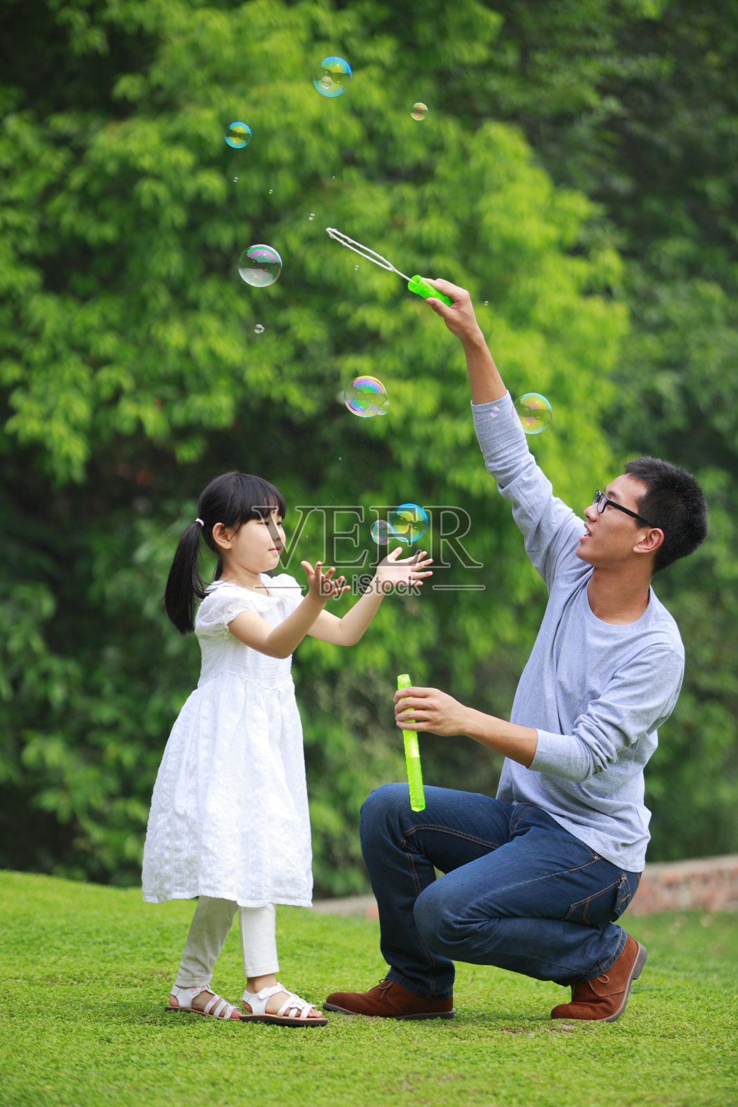 可爱的小女孩在和爸爸玩肥皂泡照片摄影图片