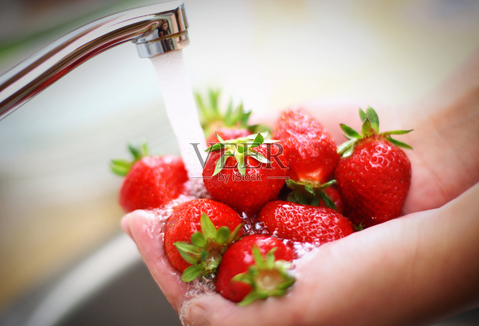 用厨房水龙头洗草莓。照片摄影图片