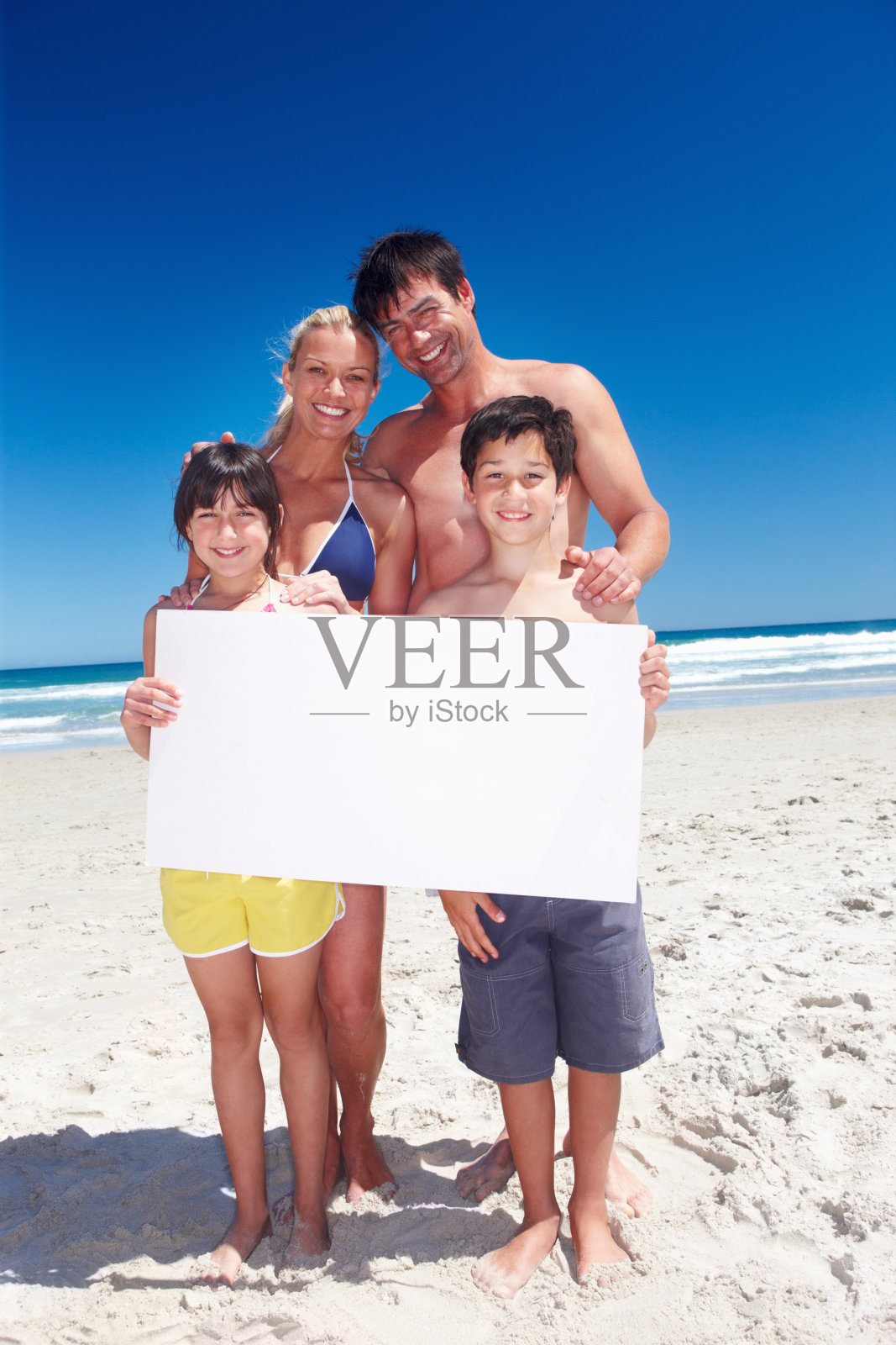 幸福的一家人在海滩上举着一个牌子照片摄影图片