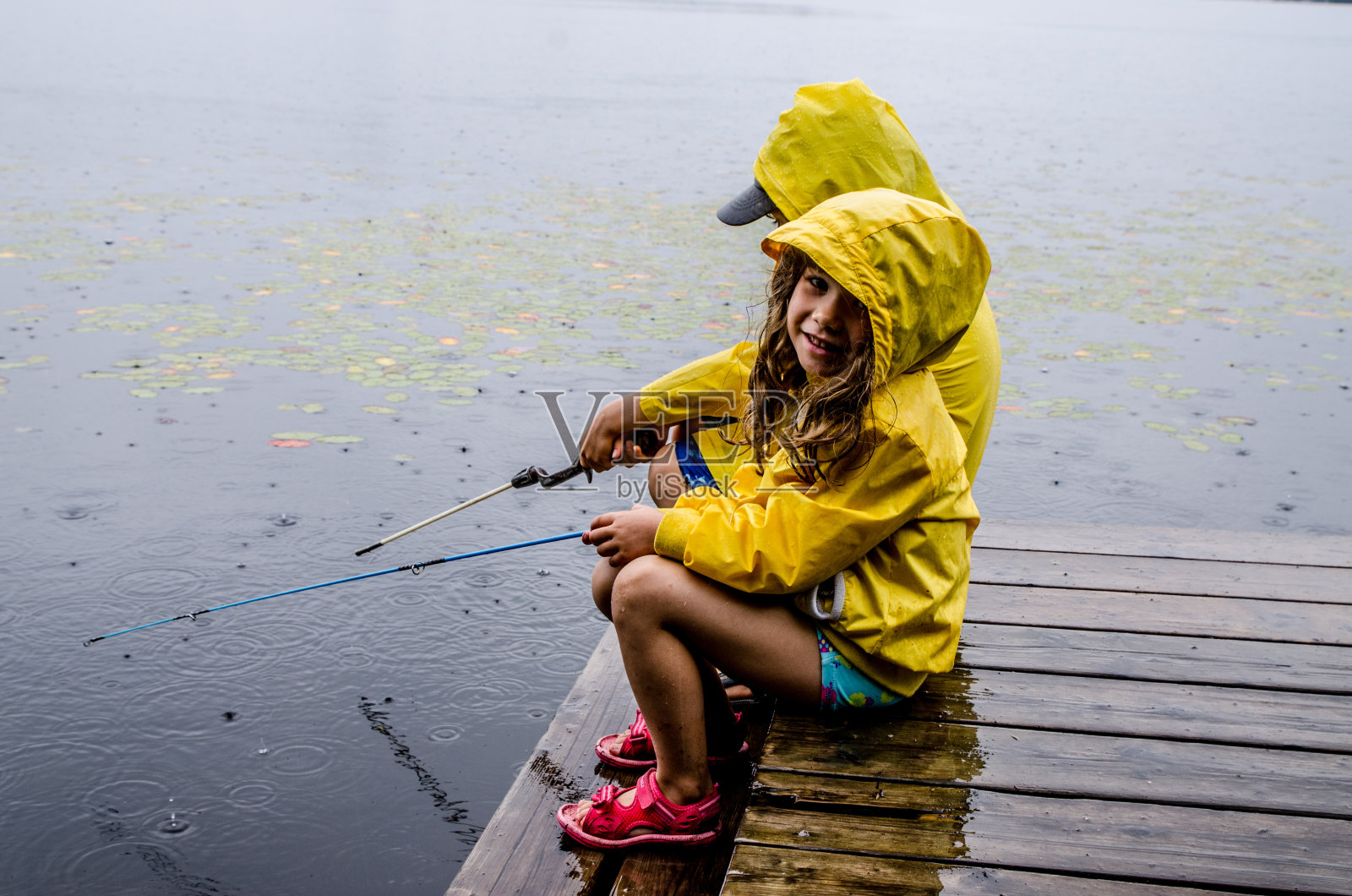 小女孩和小男孩在雨中钓鱼照片摄影图片
