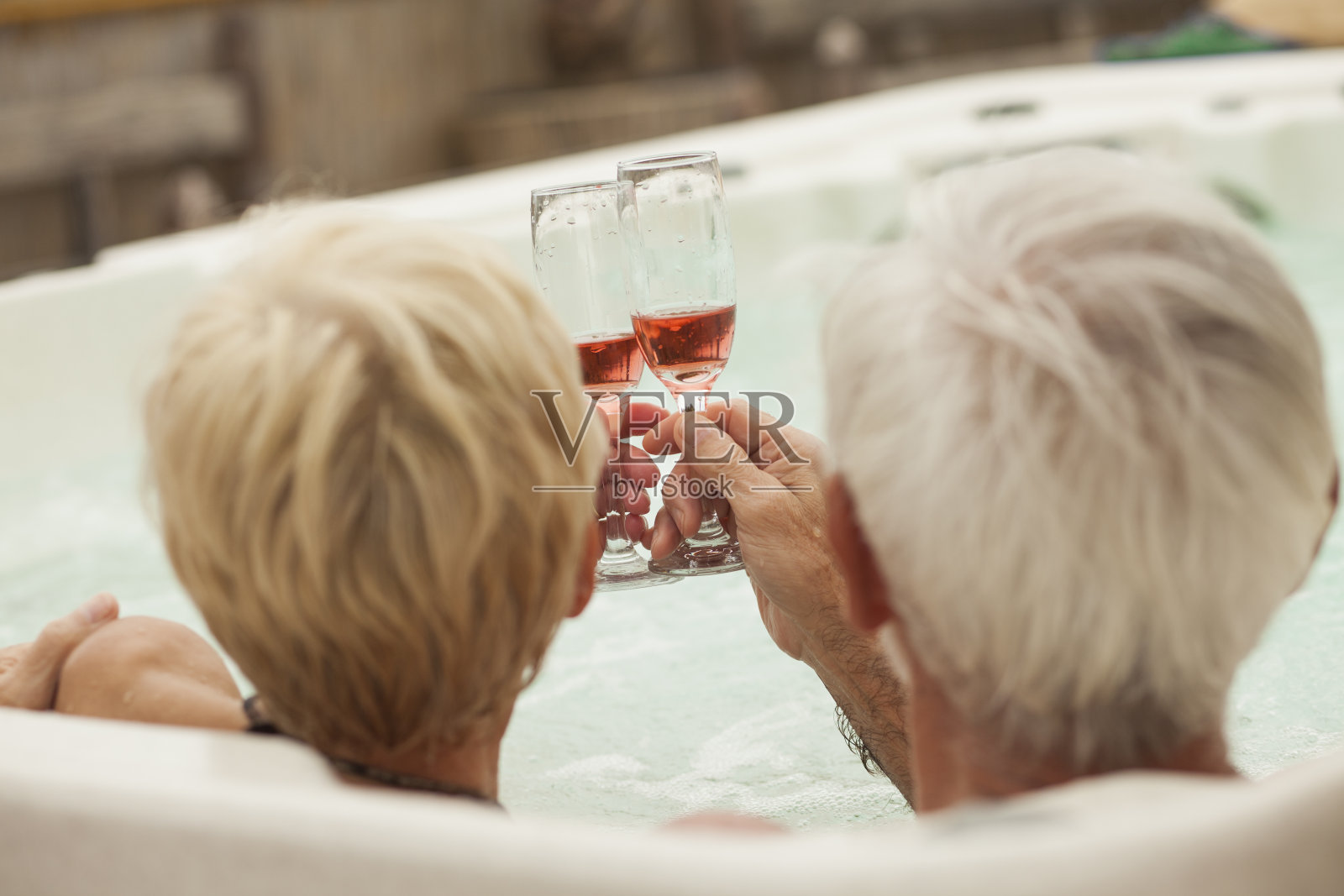 老夫妇在热浴盆里喝着香槟敬酒照片摄影图片