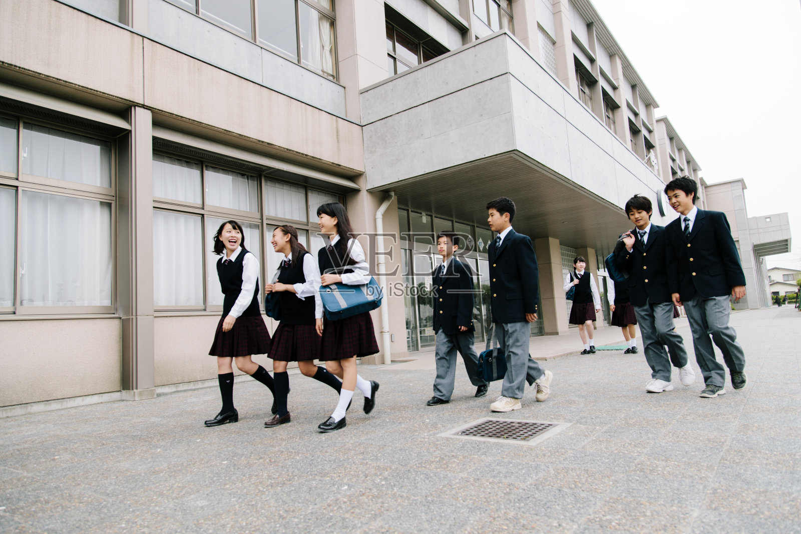 日本的高中。年轻的学生走到外面，楼外，制服照片摄影图片