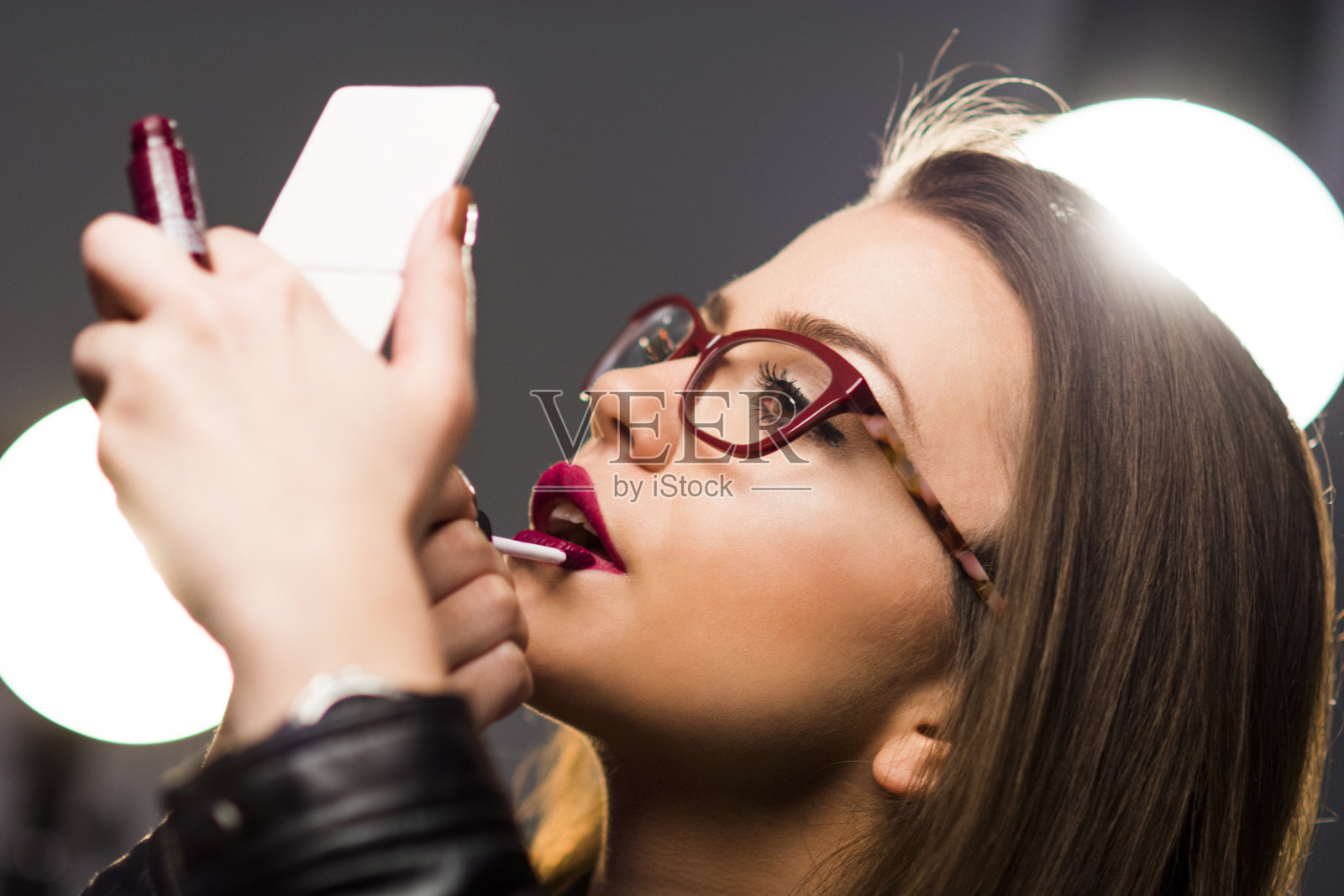 年轻女子戴着眼镜在脸上化妆照片摄影图片