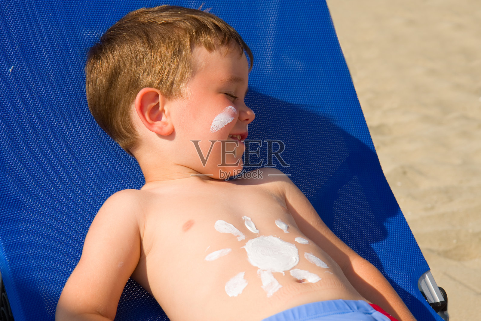 孩子躺在阳光下，肚子上放着防晒剂照片摄影图片