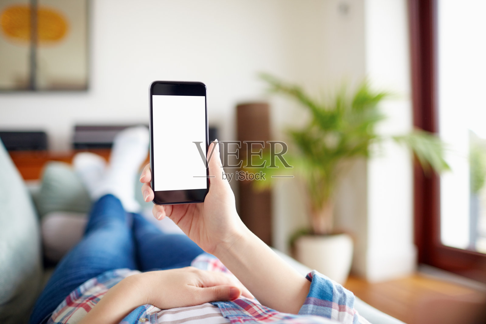 女人拿着智能手机躺在沙发上的POV照片摄影图片