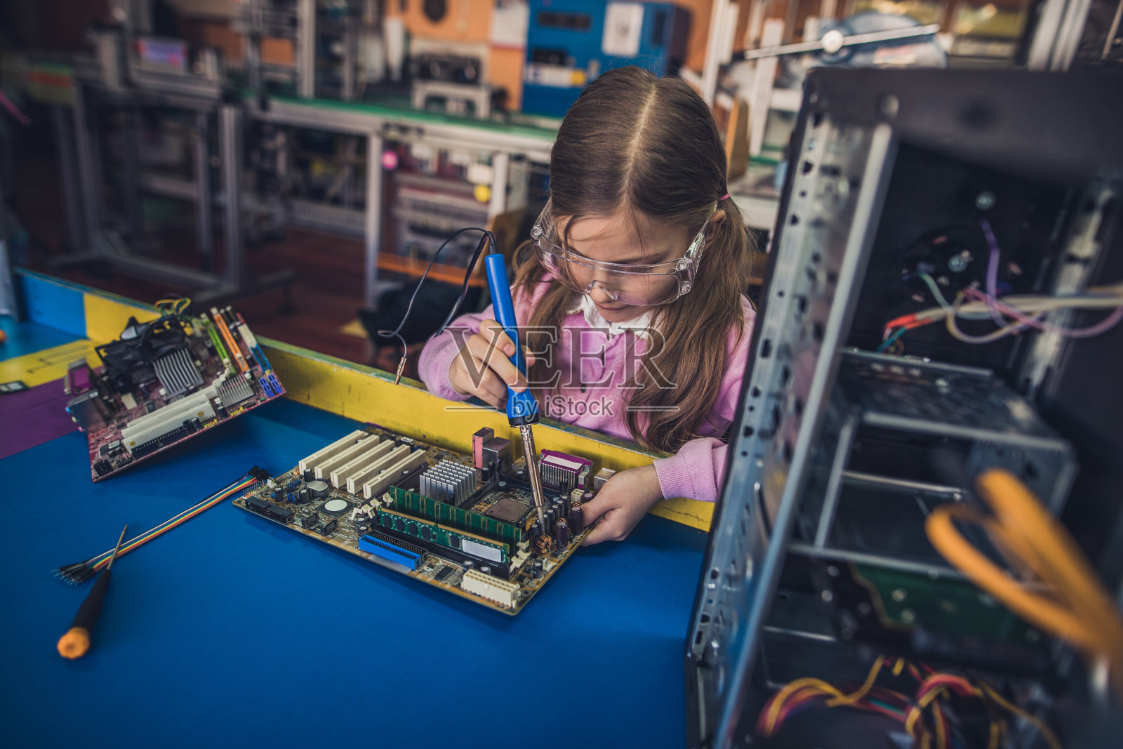 专注的小女孩在实验室焊接母板。照片摄影图片