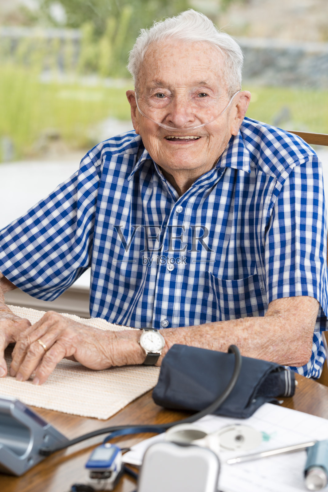 快乐的老人坐在满是医疗设备的桌子旁照片摄影图片