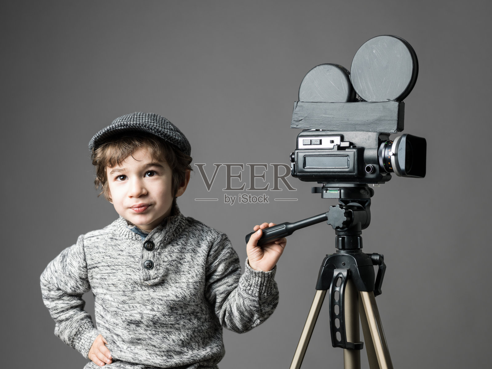 小男孩戴着平顶帽，用家用改装摄像机摆姿势照片摄影图片