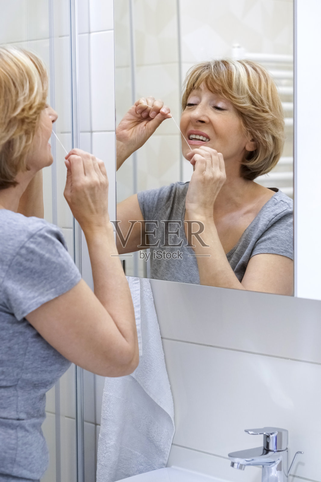 成熟的女人用牙线清洁牙齿照片摄影图片