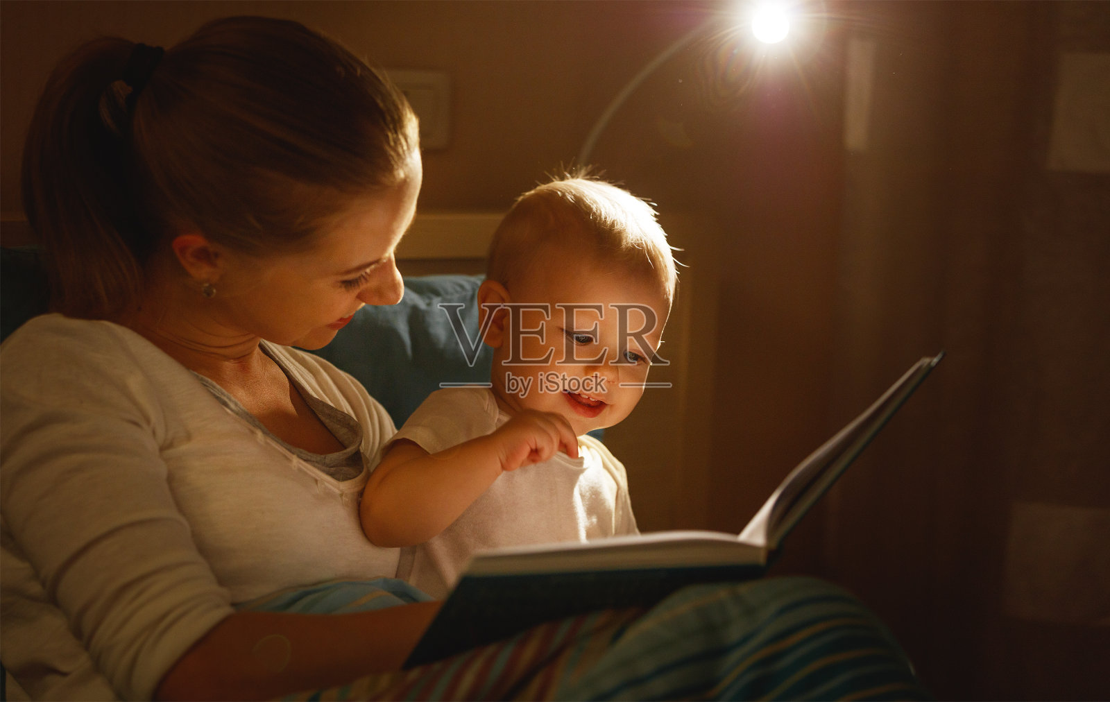妈妈在床上给婴儿读书照片摄影图片
