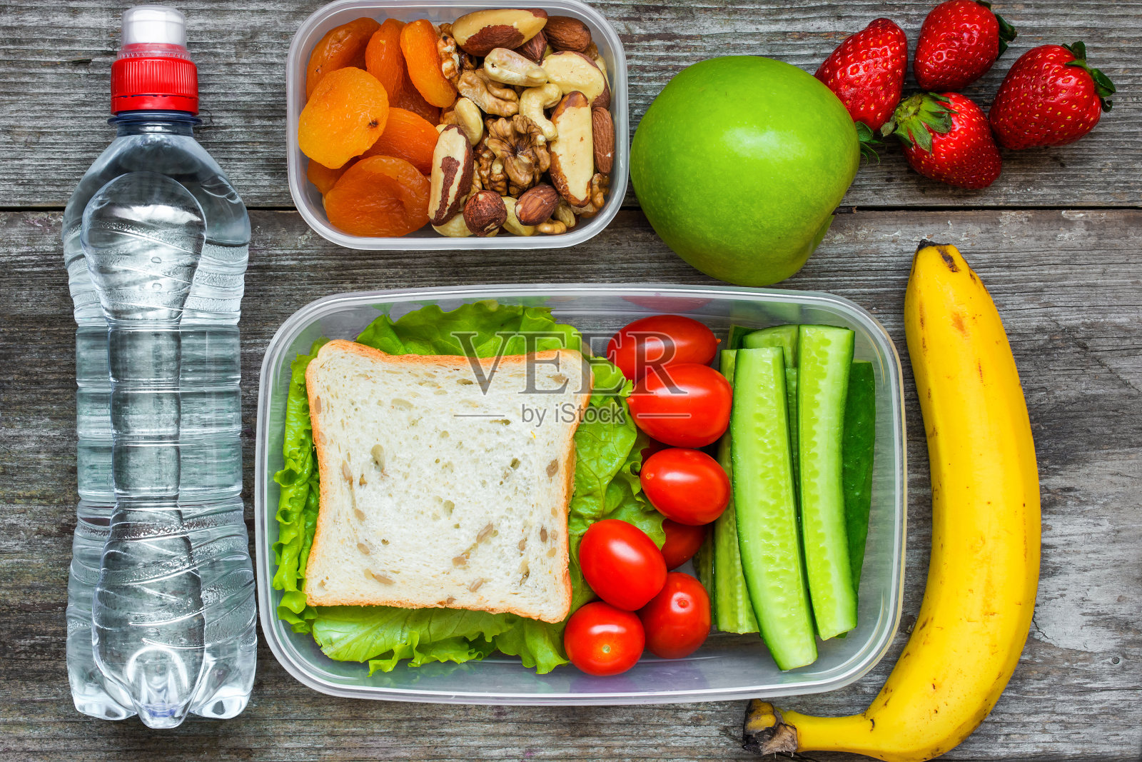 健康午餐盒，包括三明治和新鲜蔬菜，一瓶水，坚果和水果照片摄影图片