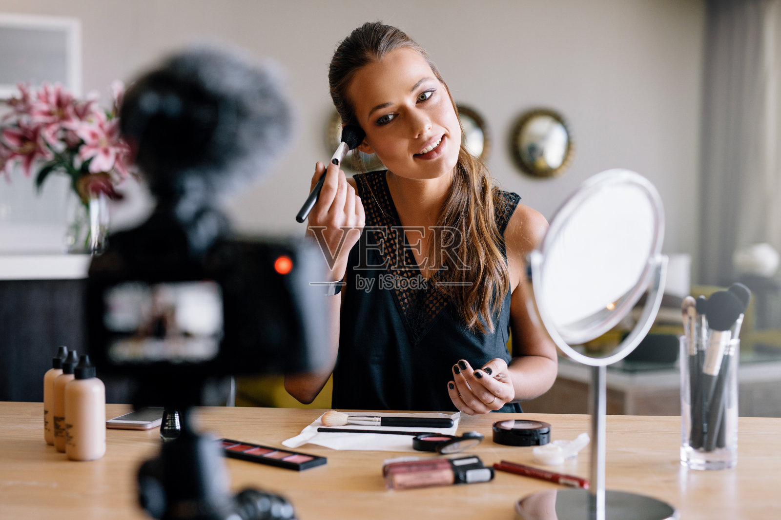年轻的女视频博主正在录制一个化妆广播。照片摄影图片