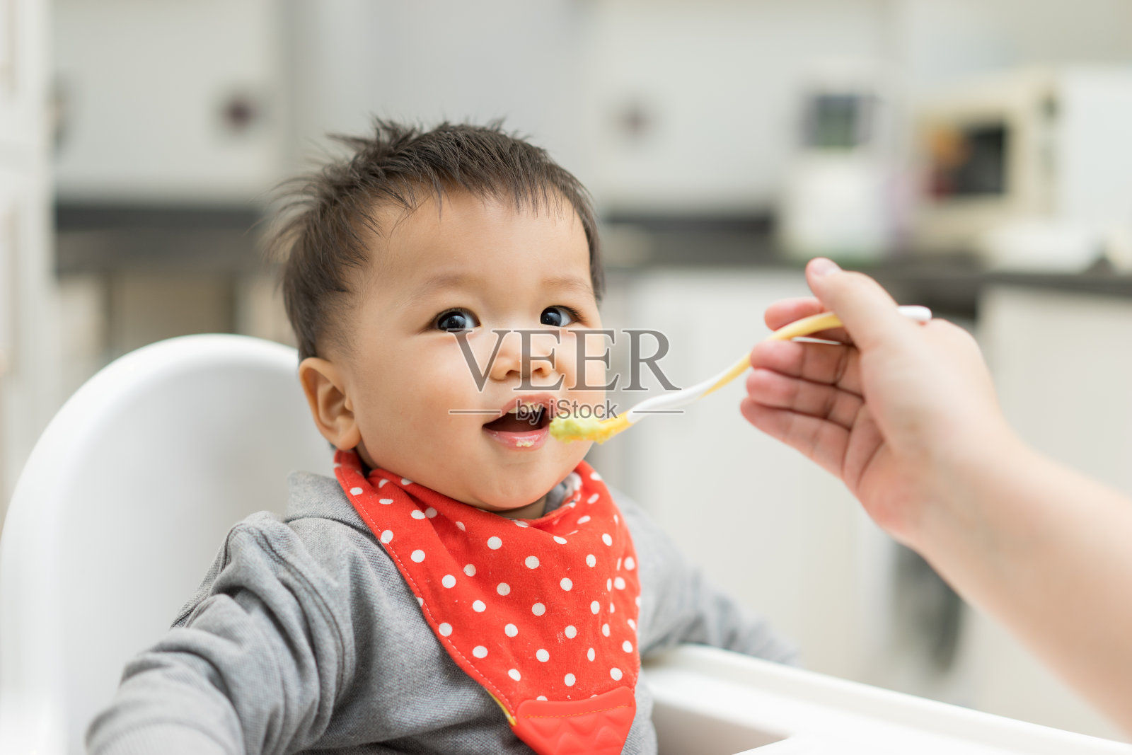 亚洲男婴在高椅子上吃混合食物照片摄影图片