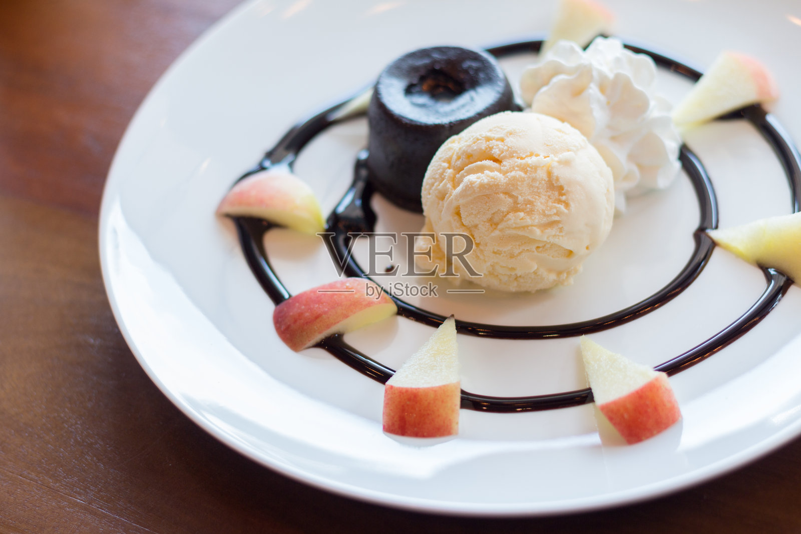 热巧克力熔岩蛋糕，香草冰淇淋球，苹果和鲜奶油照片摄影图片