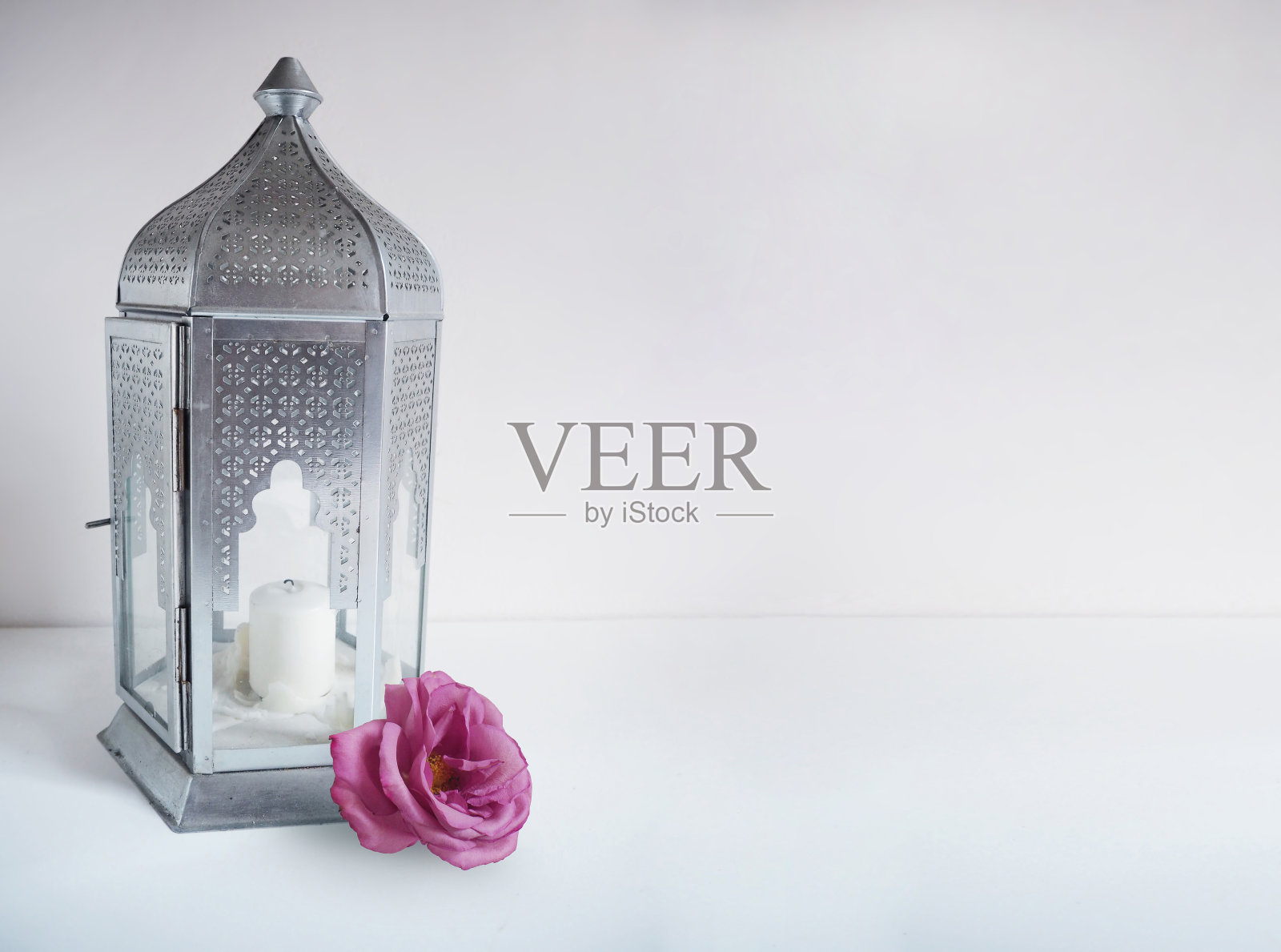 装饰性的银色阿拉伯灯笼与玫瑰花在桌子上。斋月贺卡，请帖。照片摄影图片