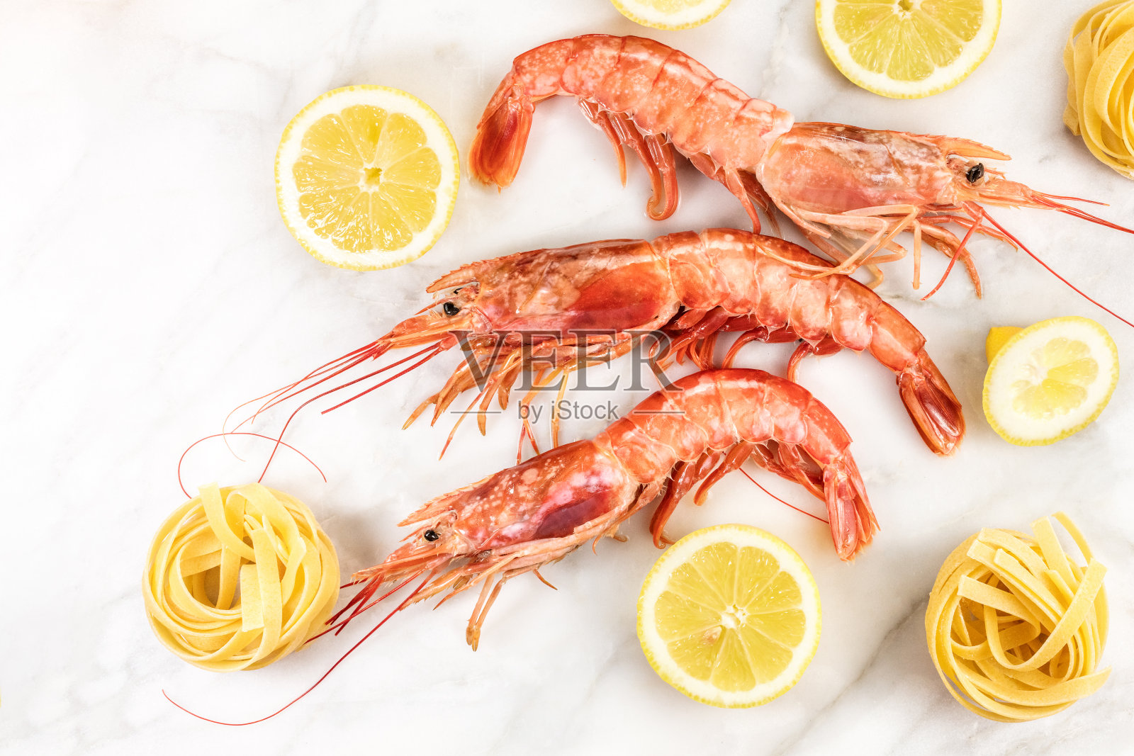 大理石桌上放着柠檬生虾和意大利面照片摄影图片
