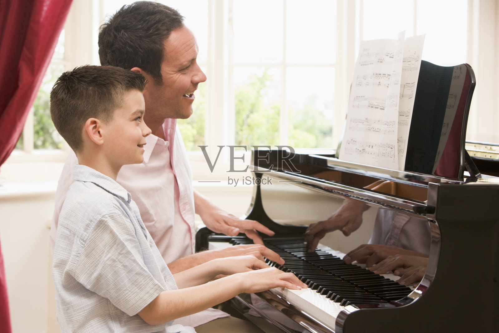 一个男人和一个小男孩读着乐谱，弹钢琴照片摄影图片