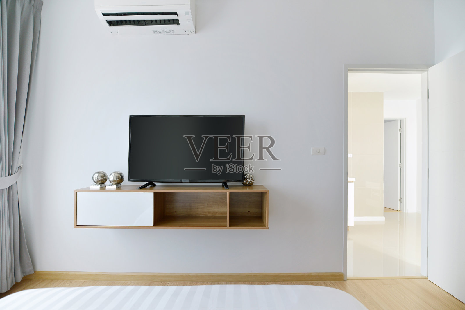 现代空卧室，白色墙壁和木制架子上的led电视照片摄影图片