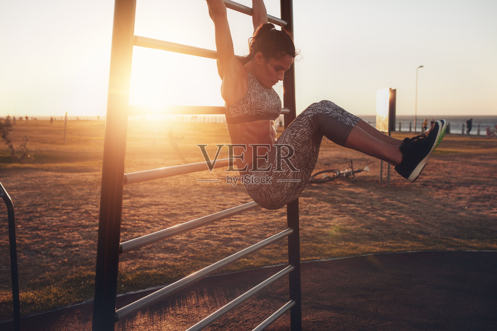 一位健康的年轻女子在日落时分在墙上锻炼。照片摄影图片