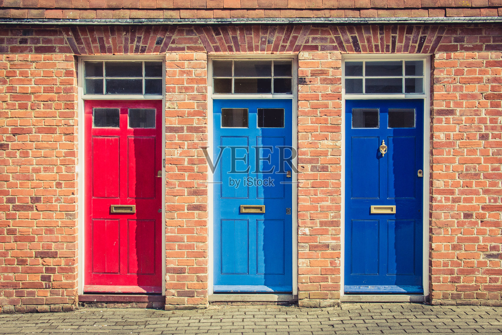 古老的英国排屋的入口处有三扇不同颜色的前门。英国的坎特伯雷。照片摄影图片