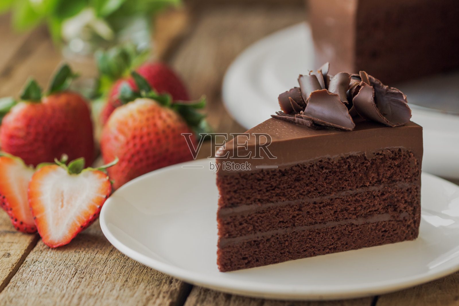 自制烘焙:用巧克力卷装饰的巧克力软糖蛋糕。咖啡、会议、茶点或茶点时间和生日聚会时，在质朴的木桌上放置三角形巧克力蛋糕。照片摄影图片