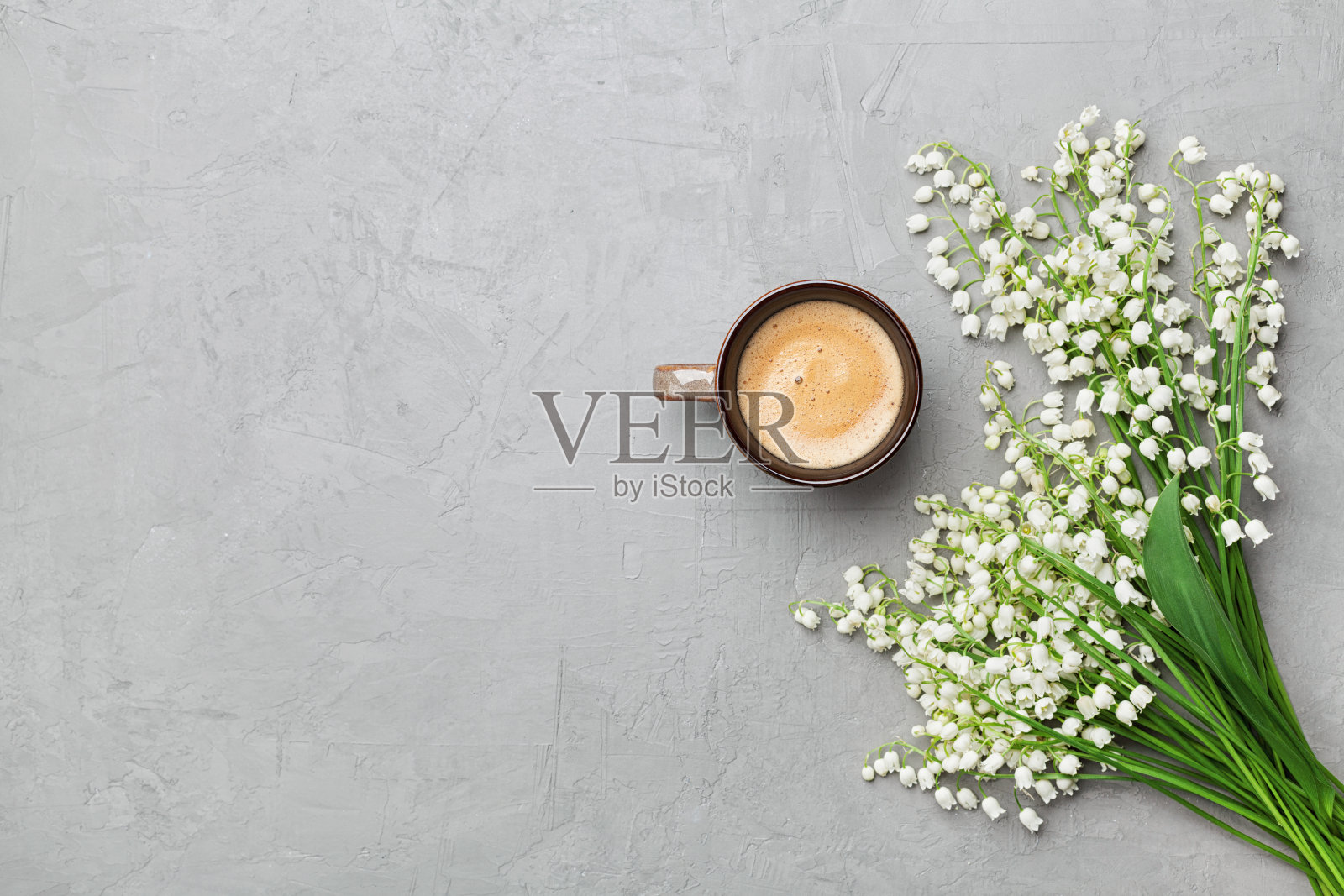 咖啡杯与花束的山谷百合在灰色的石头桌顶视图。平的。照片摄影图片